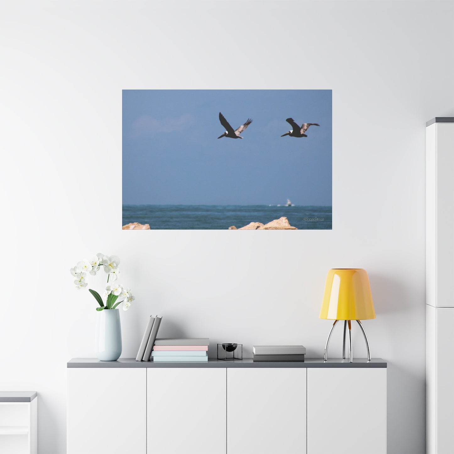 Coastal bird wall art featuring two birds flying over the ocean in a bright blue sky