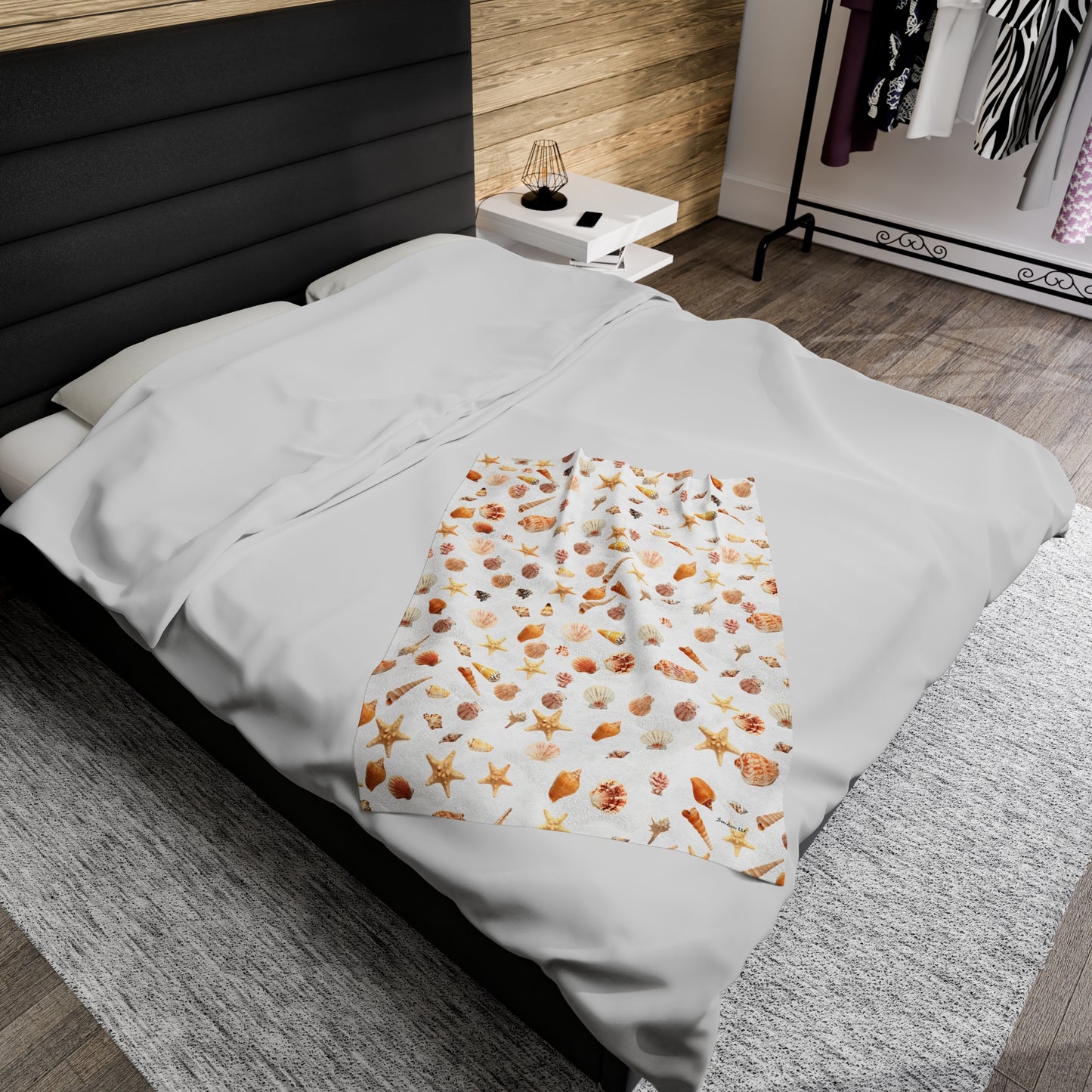 Sea shell velveteen blanket featuring a colorful ocean-themed design on a cozy bed