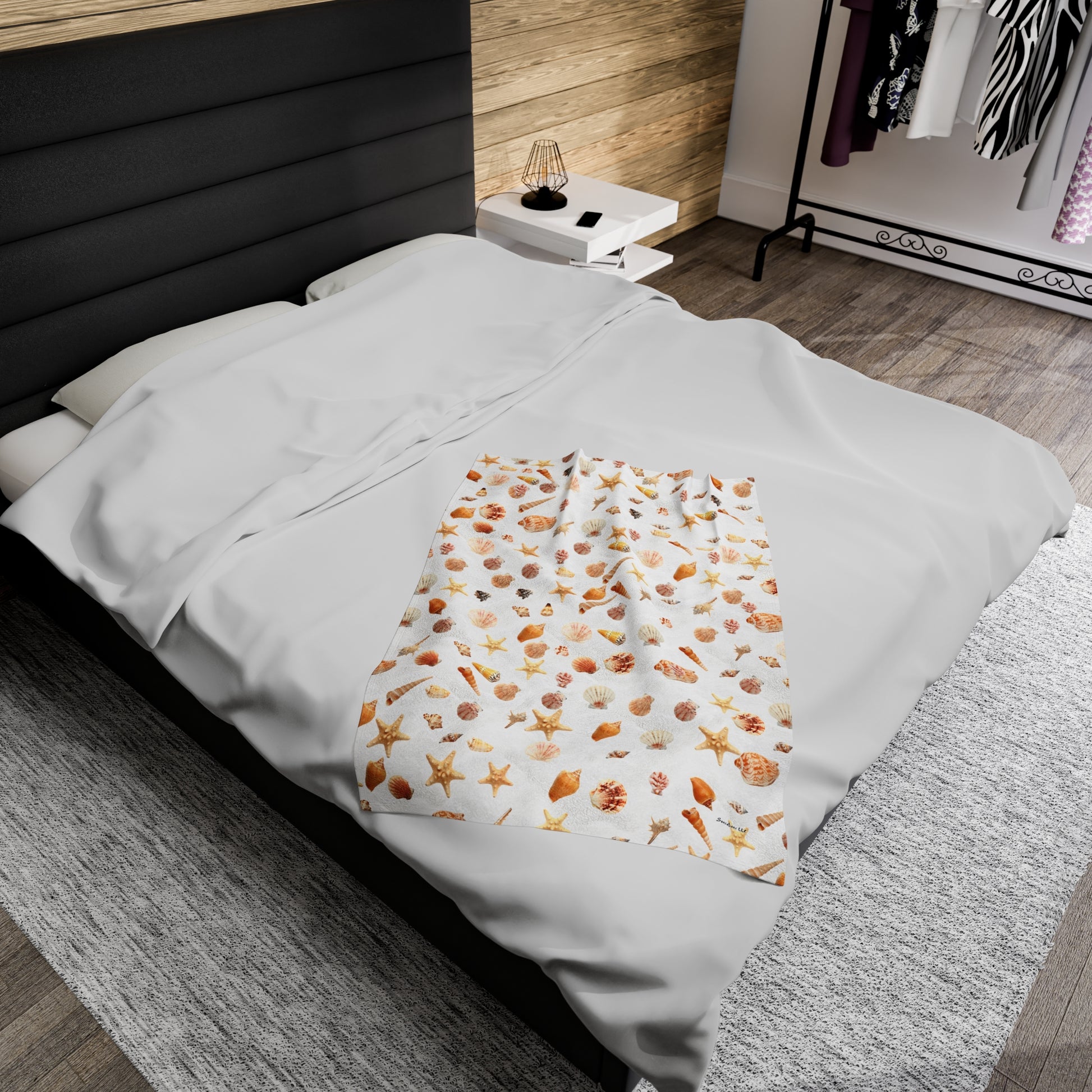 Sea shell velveteen blanket featuring a colorful ocean-themed design on a cozy bed